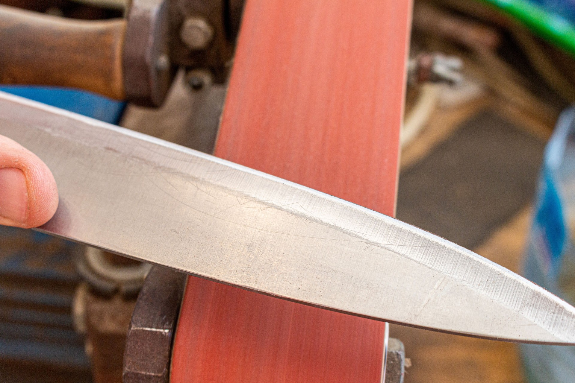 sharpening polishing kitchen knife blade on the belt grinder sander equipment. Knife making.