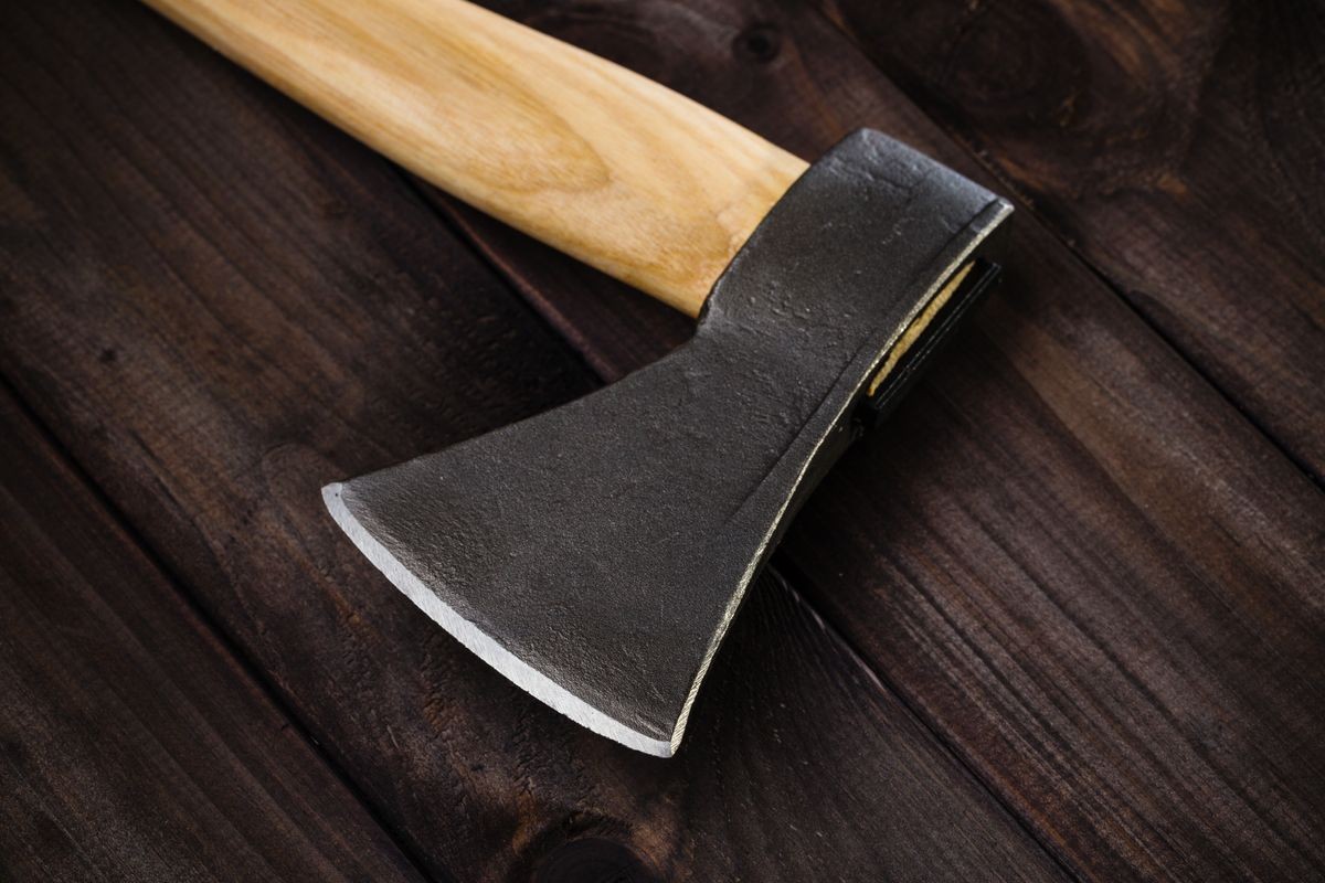 Closeup lumberjack axe on dark wooden background. Studio shot Hatchet with shiny sharp blade